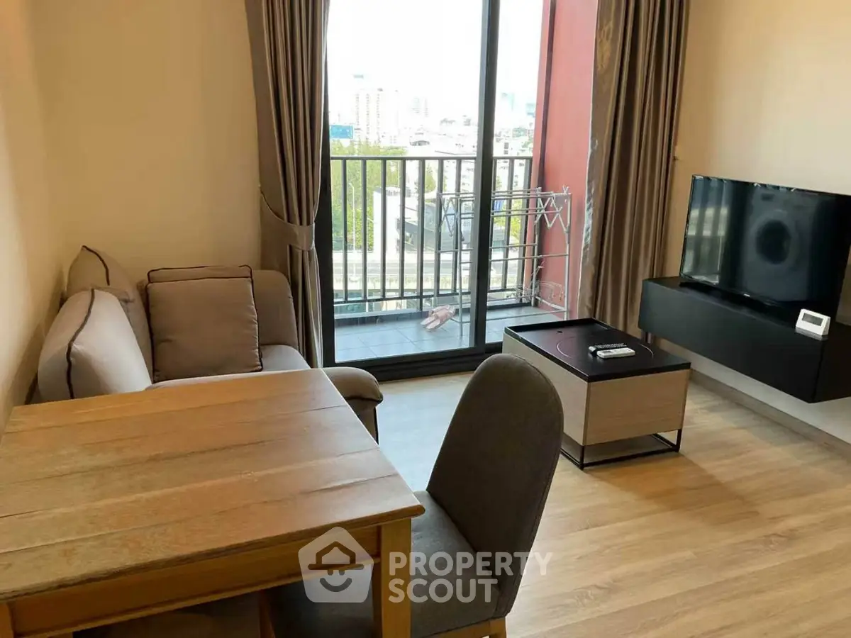Modern living room with balcony view, featuring cozy seating and sleek TV setup.
