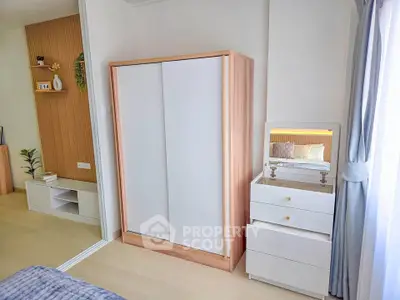 Modern bedroom with sleek wardrobe and stylish dresser, featuring natural light and elegant decor.
