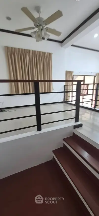 Spacious split-level living area with ceiling fan and large windows for natural light.