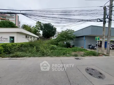 Vacant land plot on a street corner with potential for development, surrounded by urban infrastructure.