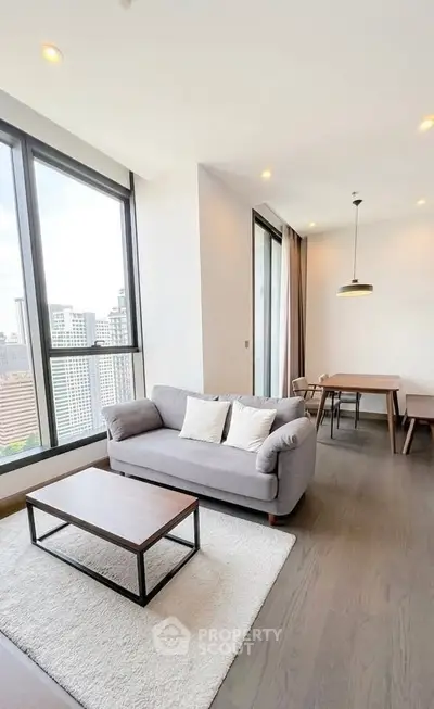 Modern living room with city view, featuring stylish furniture and large windows for natural light.