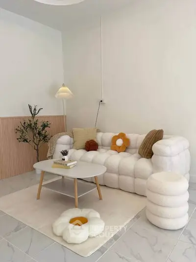 Chic modern living room with plush white sofa, stylish coffee table, and cozy decor accents.