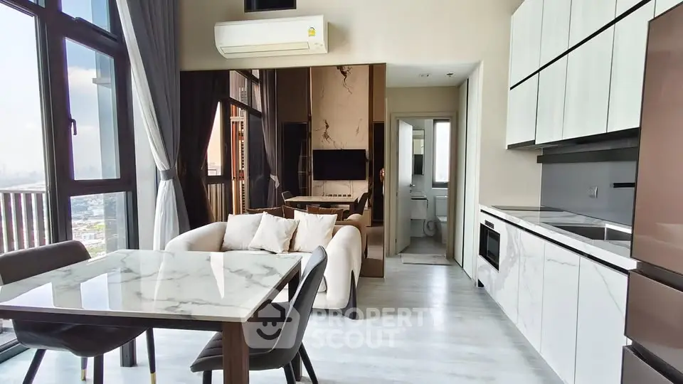 Modern open-layout living room with kitchen, featuring marble dining table and large windows with city view.
