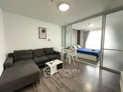 Modern living room with sleek furniture and cozy bedroom in open layout apartment.