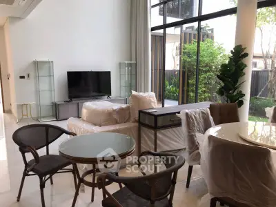 Spacious modern living room with large windows and garden view, featuring stylish furniture and elegant decor.