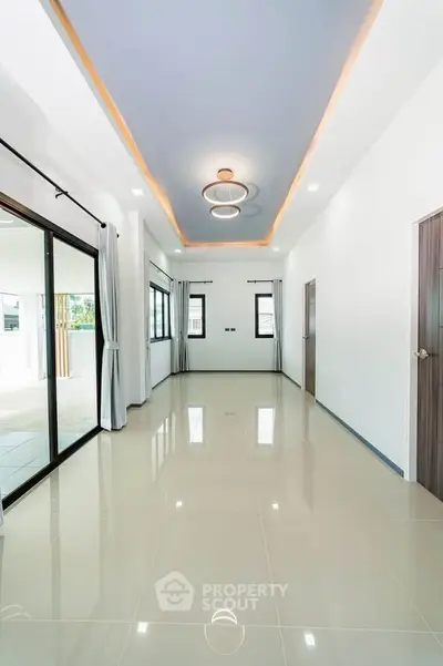 Spacious modern living room with elegant ceiling design and large windows.