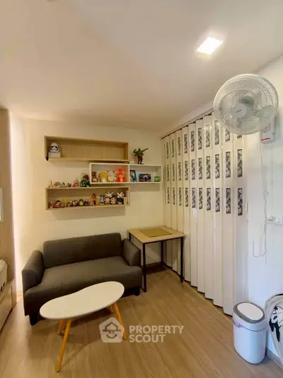 Cozy living room with modern decor and ample natural light, featuring a stylish sofa and decorative shelves.