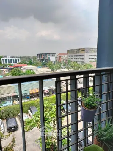 Cozy balcony with urban view, featuring potted plants and overlooking a bustling neighborhood, perfect for relaxation and city living.