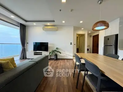 Modern living room with ocean view, stylish furniture, and open dining area.