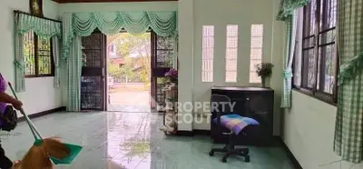 Charming living room with large windows and open entrance, featuring green curtains and tiled floor.