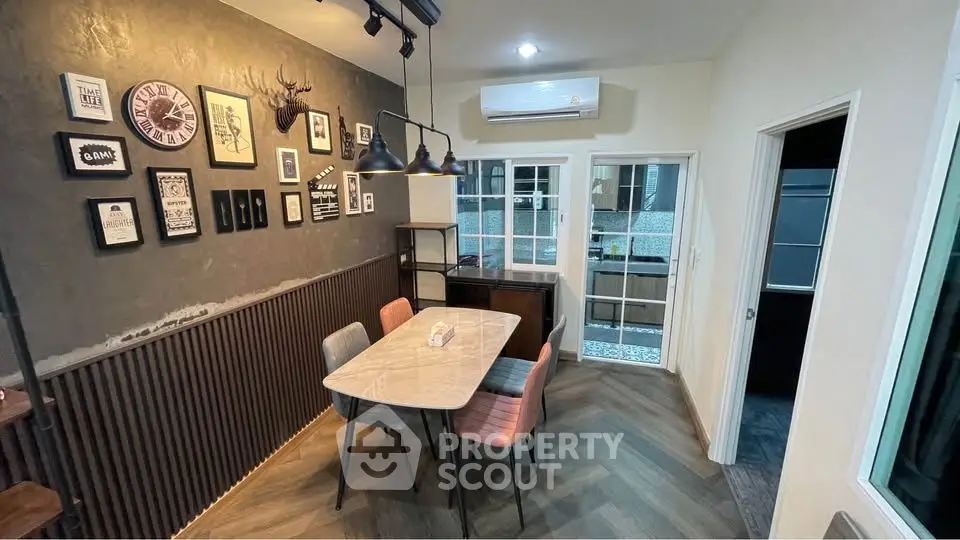 Stylish dining area with modern decor and wall art, featuring a marble table and colorful chairs.