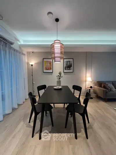 Modern dining area with stylish black table and chairs, ambient lighting, and cozy decor.