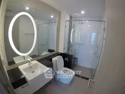 Modern bathroom with glass shower and illuminated mirror in sleek design.