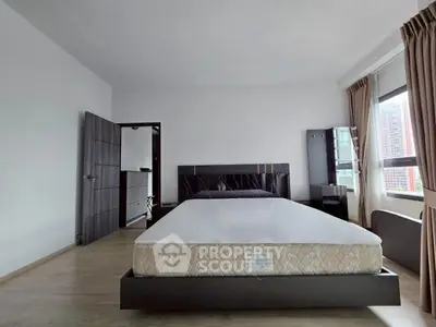 Spacious bedroom with large windows and modern furnishings in a stylish apartment.