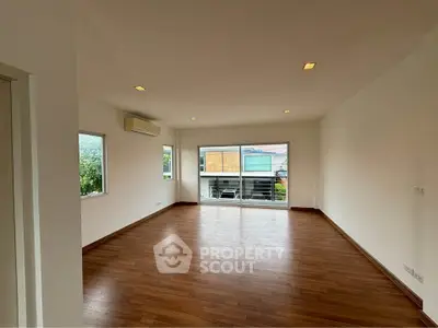 Spacious empty living room with wooden flooring and large windows for natural light.