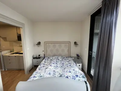Cozy bedroom with floral bedding and modern decor adjacent to a stylish kitchen.