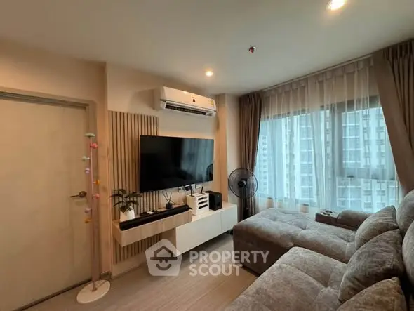 Modern living room with large TV, cozy sofa, and city view from window.