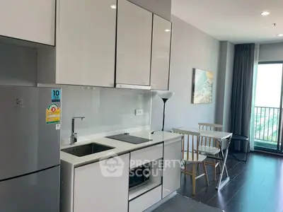 Modern kitchen with sleek cabinetry and dining area in bright apartment