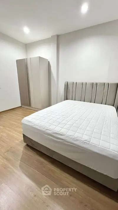 Spacious bedroom with modern design and wooden flooring, featuring a comfortable bed and sleek wardrobe.