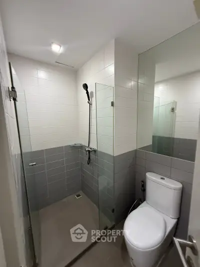 Modern bathroom with sleek shower and toilet in contemporary apartment.