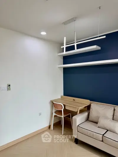 Modern living room with stylish sofa and wooden desk, featuring sleek shelving and contemporary lighting.