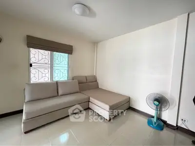Cozy living room with modern sectional sofa and fan, perfect for relaxation.
