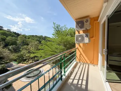 Spacious balcony with lush green view and air conditioning units, perfect for relaxation.