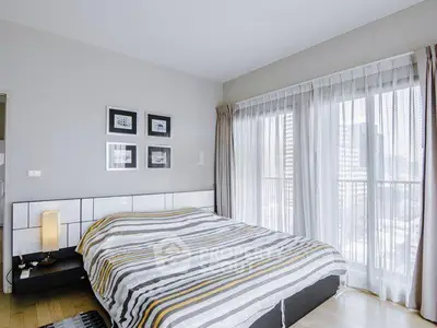 Modern bedroom with large windows and stylish decor in urban apartment.