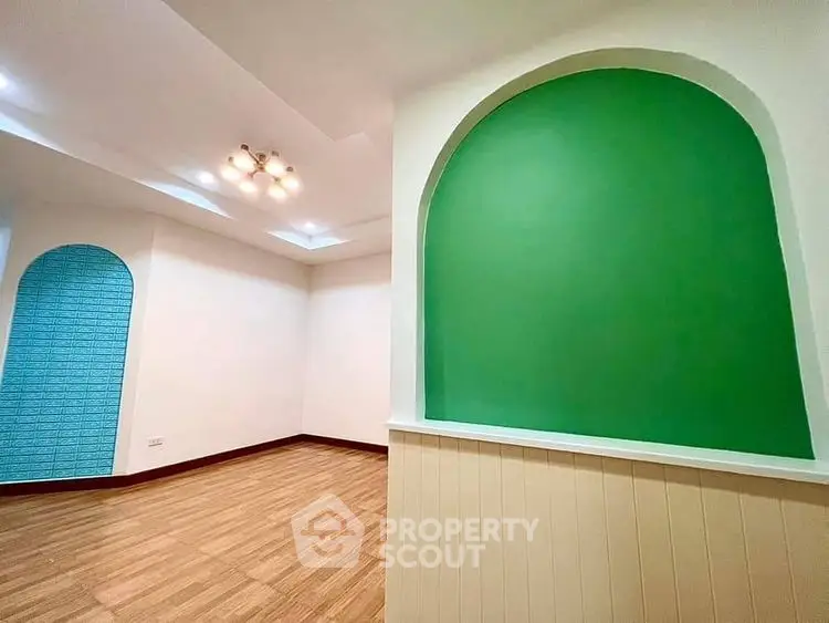 Spacious living room with unique green accent wall and modern lighting