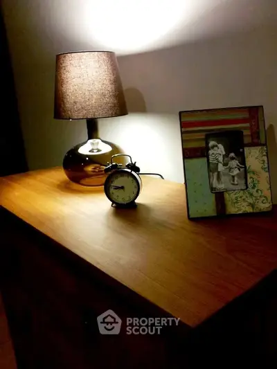 Cozy bedroom nightstand with lamp, clock, and framed photo, perfect for a warm ambiance.