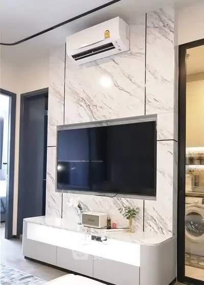 Modern living room with marble wall, large TV, and air conditioning unit