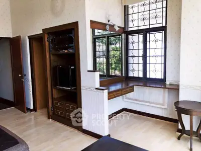 Charming living room with built-in wooden shelves and large windows offering natural light.