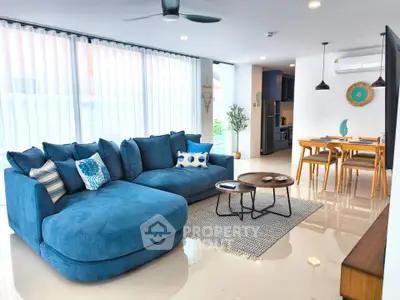Spacious modern living room with stylish blue sofa and dining area, perfect for family gatherings.