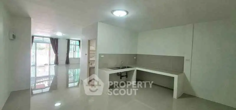 Spacious open-plan living area with modern kitchen and large windows for natural light.