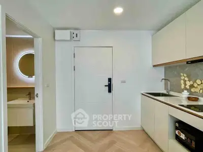 Modern kitchen with sleek cabinetry and adjacent bathroom featuring a stylish round mirror.