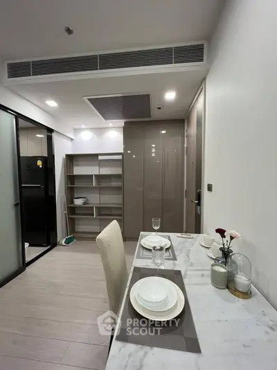 Modern dining area with sleek table setting and open kitchen layout in a stylish apartment.