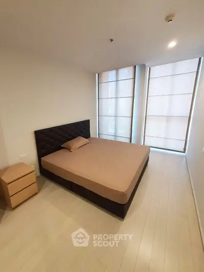 Modern bedroom with large windows and minimalist design, featuring a comfortable bed and sleek flooring.