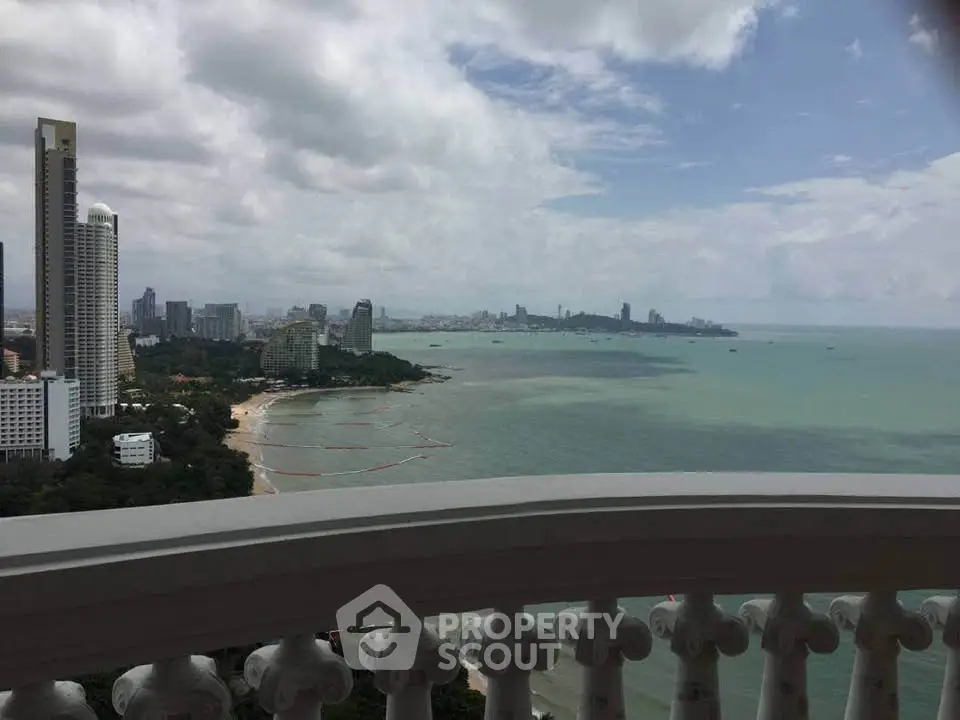 Stunning coastal cityscape view from a high-rise balcony, showcasing expansive ocean and skyline.