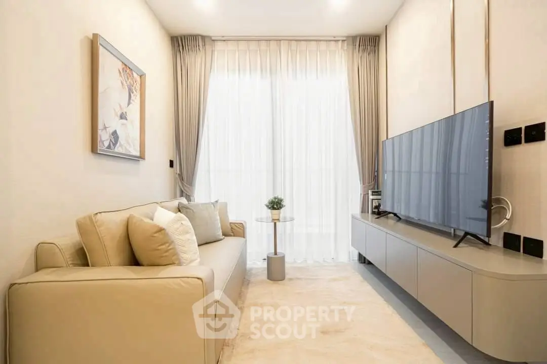 Modern living room with sleek furniture and large TV, featuring elegant decor and natural light.