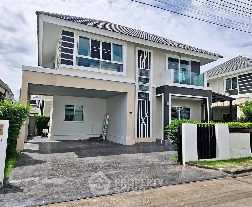 Modern two-story house with sleek design and spacious driveway in a suburban neighborhood.