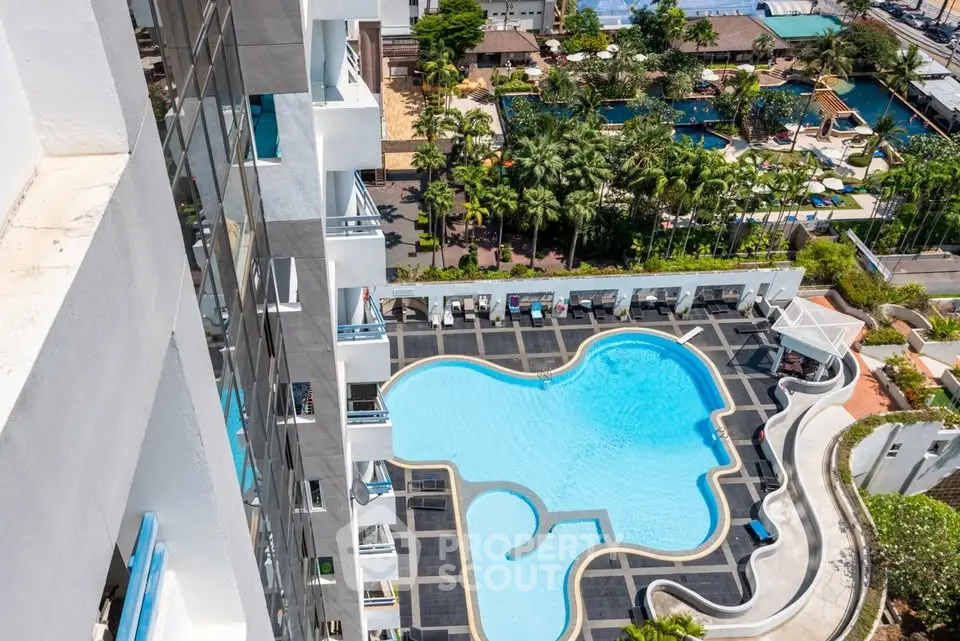 Stunning aerial view of luxury apartment building with unique pool design and lush surroundings.