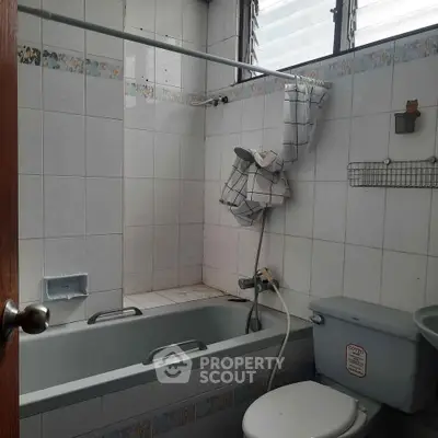 Cozy bathroom with bathtub and tiled walls, featuring a shower curtain and compact layout.