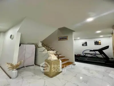Modern home gym with treadmill and elegant staircase in stylish interior.