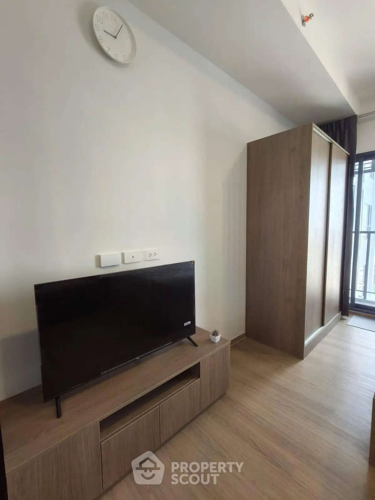 Modern living room with sleek TV stand and large wardrobe, featuring minimalist design and natural light.