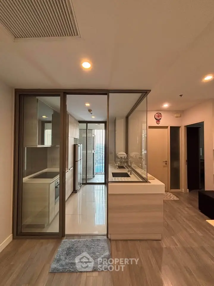 Modern kitchen with glass partition and sleek appliances in a stylish apartment.