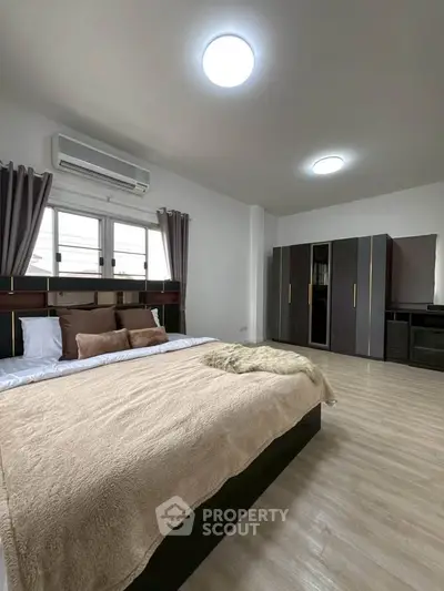 Spacious modern bedroom with stylish decor and ample natural light, featuring a large bed and sleek wardrobe.
