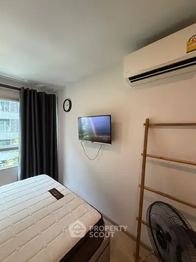 Cozy bedroom with air conditioning, wall-mounted TV, and large window for natural light.