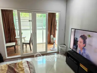 Cozy bedroom with balcony access and modern TV setup, perfect for relaxation and entertainment.