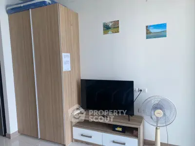 Modern living room with sleek TV stand, wardrobe, and fan, perfect for cozy urban living.