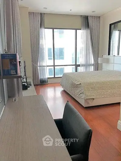 Spacious bedroom with large window and elegant decor in modern apartment.